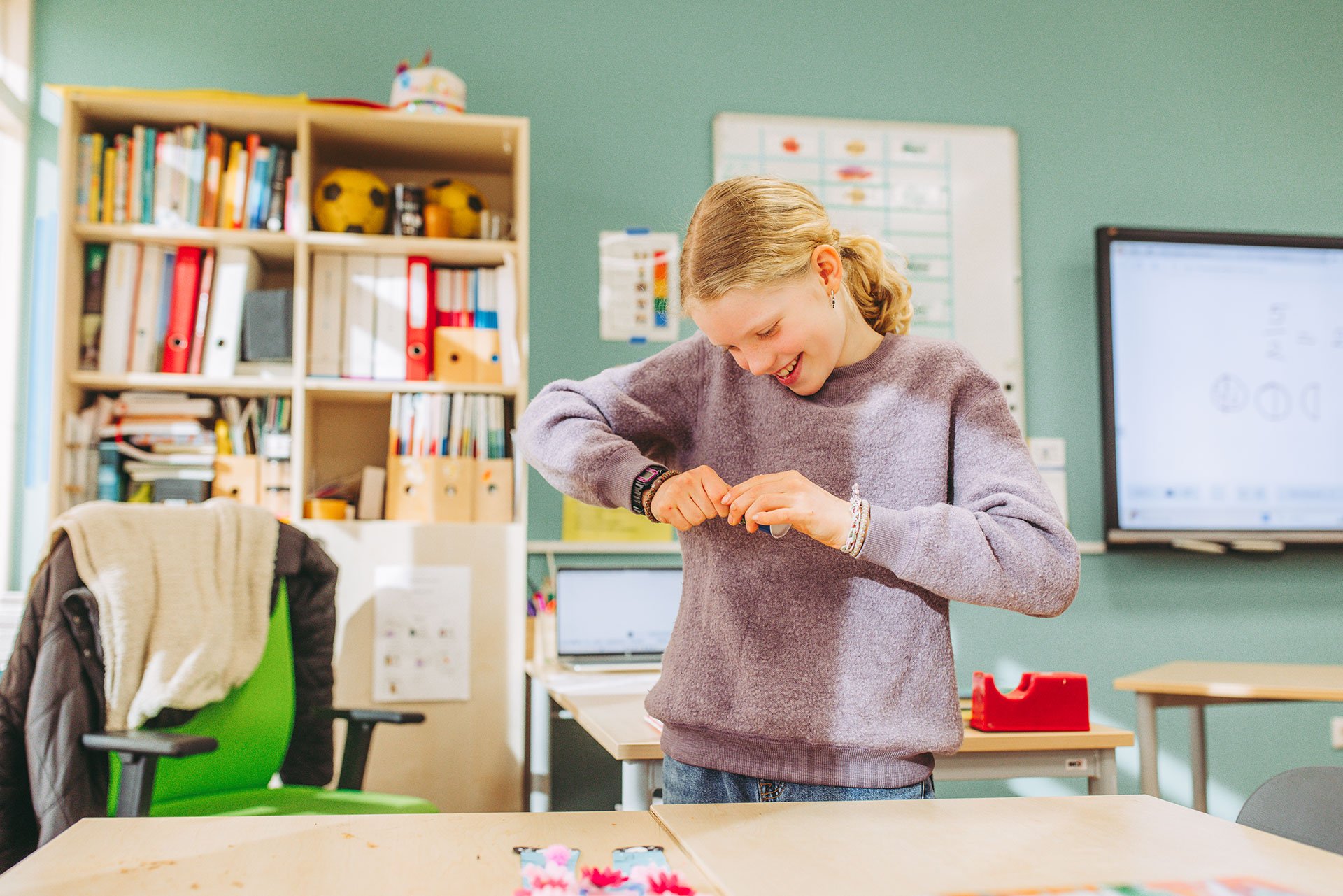 jongen loopt op het plein richting de foto, op de achtergrond een basket en speeltoestellen